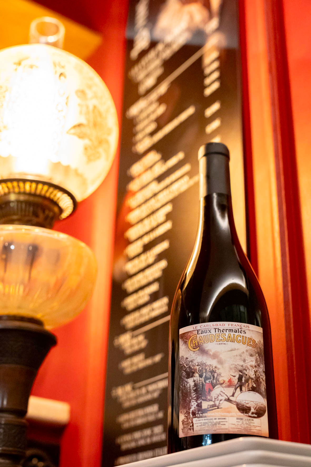 Lampe allumée et bouteille liée aux eaux thermales de Chaudes-Aigues, ambiance intérieure chaleureuse hors saison