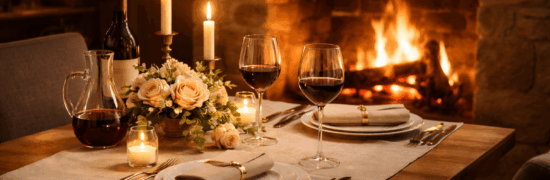 Table dressée pour un dîner romantique à Chaudes-Aigues, avec bougies, verres de vin rouge et feu de cheminée en hiver
