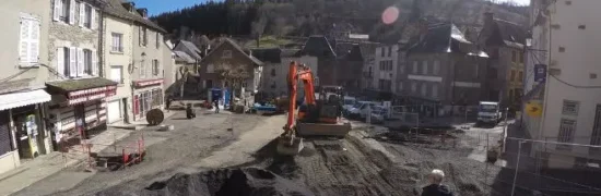 Travaux de voirie sur la place du marché de Chaudes-Aigues révélant les réseaux et le sous-sol du cœur de village